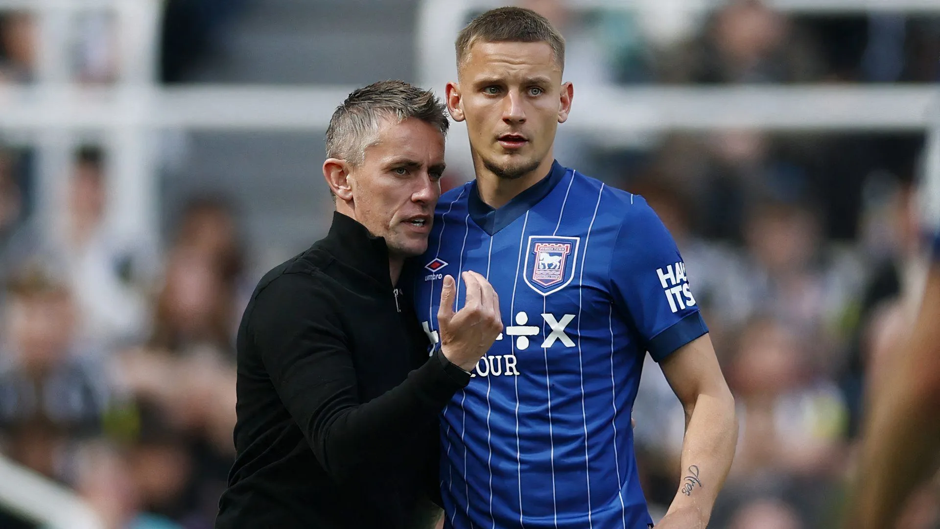 Huấn luyện viên Kieran McKenna của Ipswich Town và cầu thủ Luke Woolfenden thảo luận trên sân tập, thể hiện sự chuẩn bị cho mùa giải mới